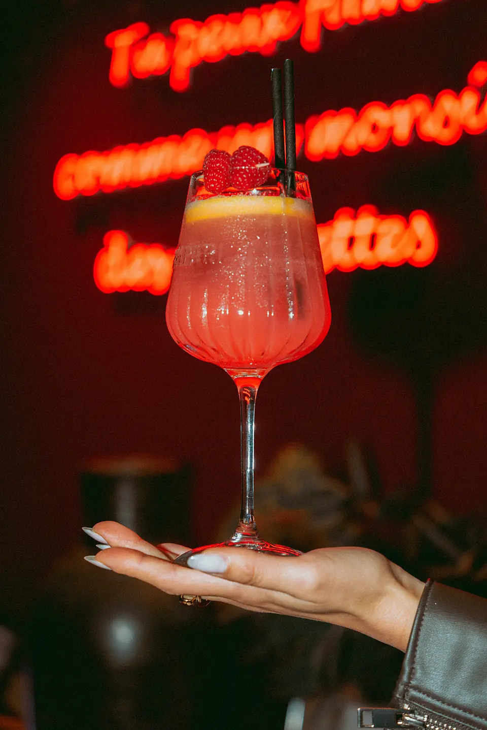 Un spritz tenu devant le néon rouge